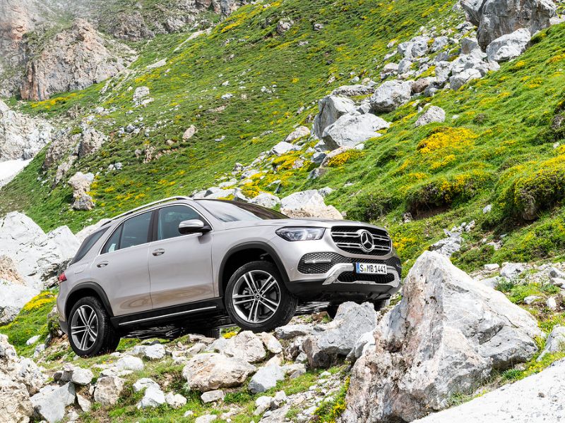 silver mercedes gle driving in the alps over rocks