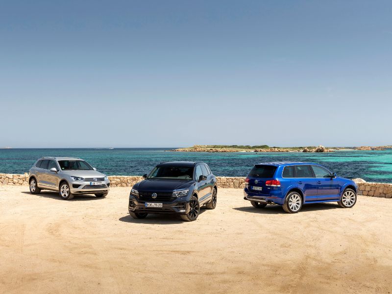 2003 to present volkswagen touaregs blue first generation touareg silver second generation touareg and black current generation touareg standing at the beach
