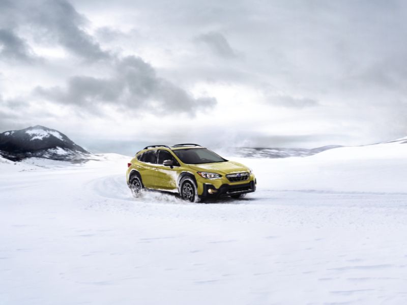 2023 golden yellow subaru crosstrek sport driving in snow in the mountains