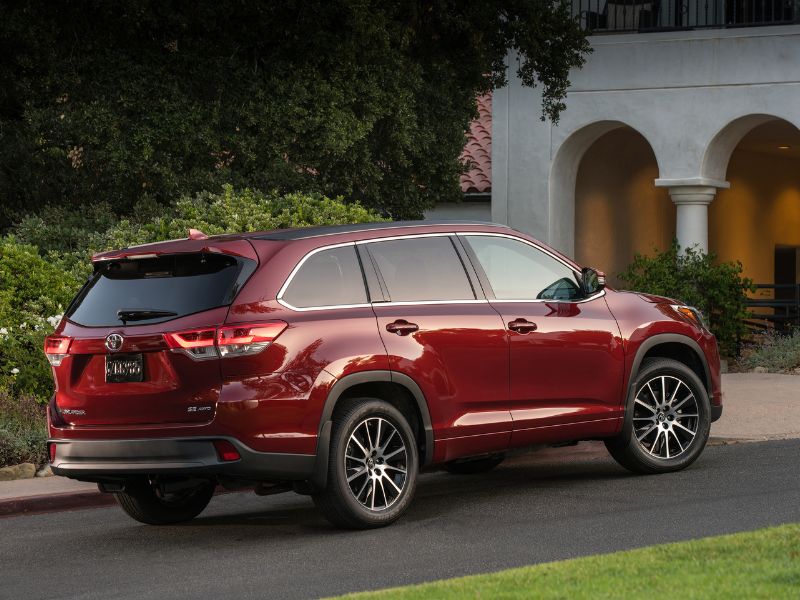 2017 red metallic Toyota Highlander SE in a driveway of a high end house
